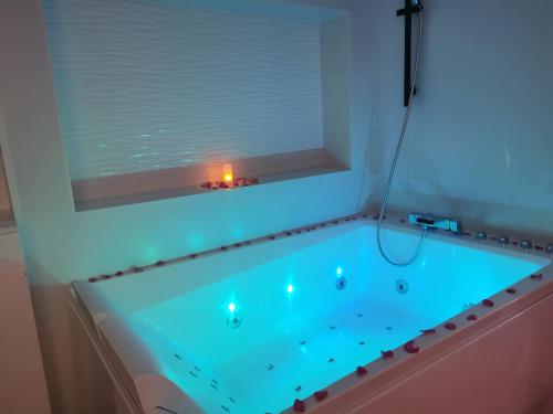 Villeneuve-de-la-Raho的住宿－Splendide Suite LOVE ROOM avec JACUZZI PRIVATIF，浴缸内有蓝色的灯光