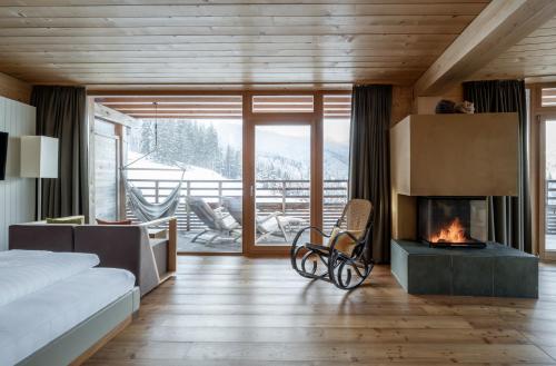 a bedroom with a fireplace and a bed and a couch at Holzhotel Forsthofalm in Leogang