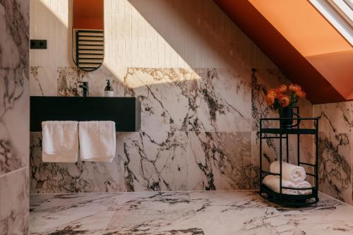 a bathroom with marble walls and a sink and towels at WELTWIEN Luxury Art Apartments in Vienna