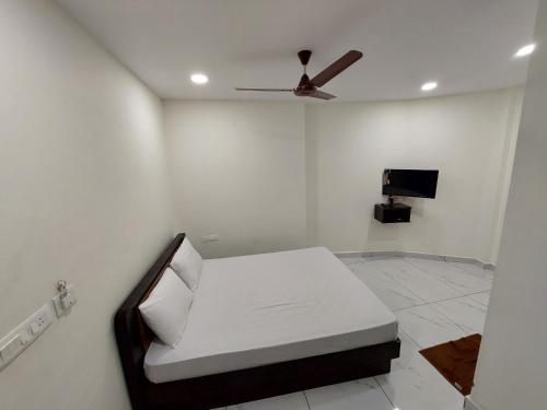 a white room with a bed and a ceiling fan at Aman Residency in Thodupuzha