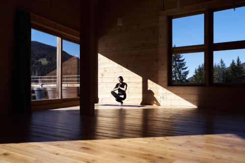 a person squatting in a room with windows at Holzhotel Forsthofalm in Leogang