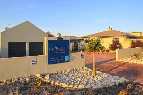 a sign in front of a house with a tree at Le Mahi Guest House in Langebaan