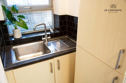 a kitchen with a stainless steel sink and a window at 2 bed Apartment by UK Corporate Relocations Ltd in Warrington