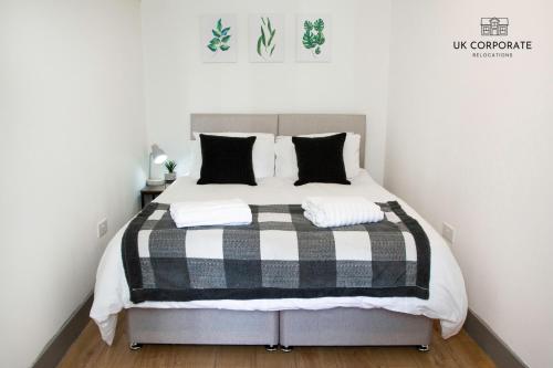 ein Schlafzimmer mit einem Bett mit einer schwarzen und weißen Decke in der Unterkunft 2 bed Apartment by UK Corporate Relocations Ltd in Warrington