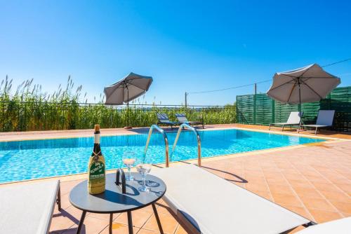 a bottle of wine on a table next to a swimming pool at Villa Erasmia in Vlachata