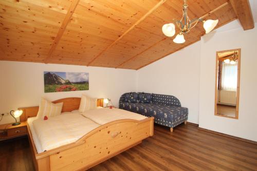 a bedroom with a wooden bed and a couch at Obermooshof in Fügenberg