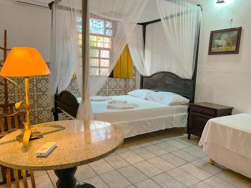 een slaapkamer met een bed en een tafel met een lamp bij Pousada dos Candeeiros in Carolina