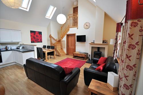 a living room with a black couch and a kitchen at Rose Cottage at Williamscraig Holiday Cottages in Linlithgow