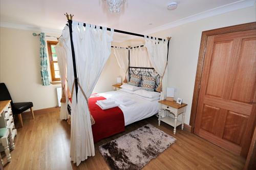 a bedroom with a bed with a mosquito net at Rose Cottage at Williamscraig Holiday Cottages in Linlithgow