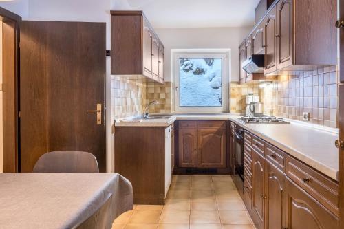 a kitchen with wooden cabinets and a window at Sirena Carezza Apartment Regenbogen in Carezza al Lago