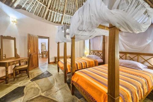 a bedroom with two beds and a desk and a bedvisor at Tiwani Sunset, a little piece of Eden in Tiwi