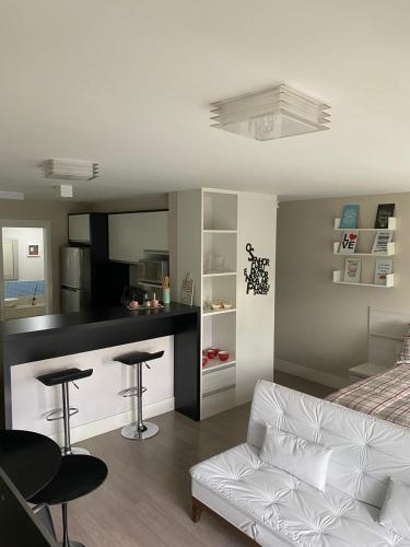 een woonkamer met een witte bank en een keuken bij LINDO LOFT, PISCINA, ESTACIONAMENTO, ACADEMIA, AR CONDICIONADO, Wi-Fi in Sao Paulo