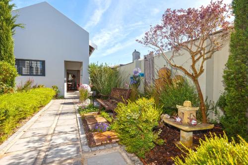 a garden with a bench and a tree in a yard at Le Mahi Guest House in Langebaan