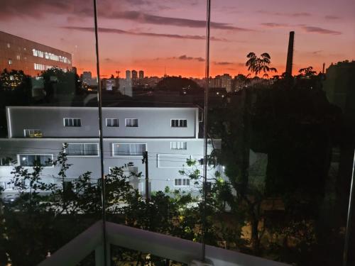 聖保羅的住宿－LINDO LOFT, PISCINA, ESTACIONAMENTO, ACADEMIA, AR CONDICIONADO, Wi-Fi，享有建筑美景,背景是日落