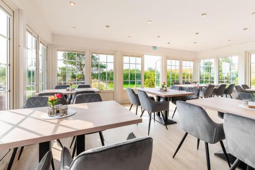 un restaurante con mesas, sillas y ventanas en Nordsee-Hotel Arlau-Schleuse, en Husum