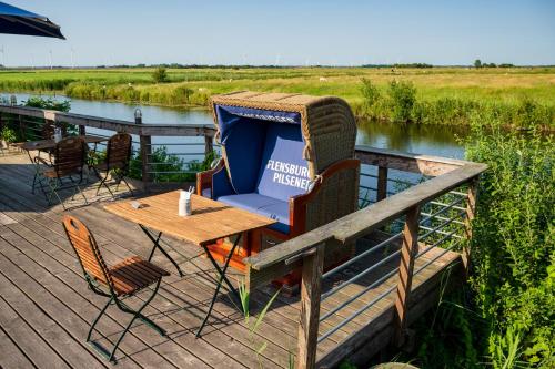 a wooden deck with a table and chairs next to a river at Nordsee-Hotel Arlau-Schleuse in Husum