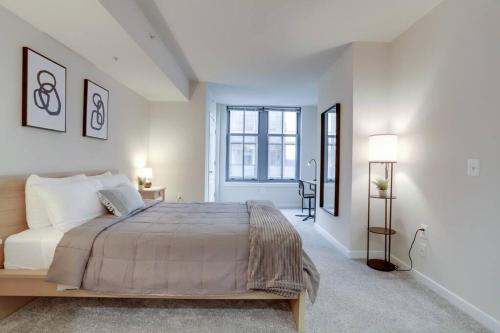 a white bedroom with a large bed and a window at Splendid 2 BR Condo At Pentagon City in Arlington