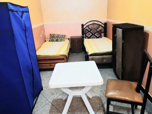 Cette chambre comprend deux lits, une table et une chaise. dans l'établissement Zitouna Rooms, à Casablanca