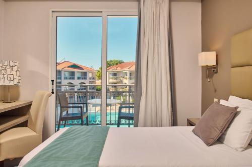 a bedroom with a bed and a view of a balcony at Tsilivi Beach Hotel Zakynthos in Tsilivi