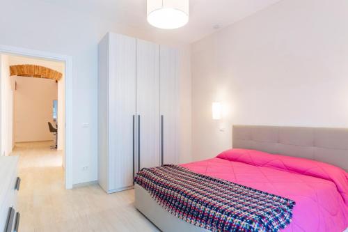 a bedroom with a pink bed and a white closet at Casa L - Mimbelli Park Modern Quiet Apartment in Livorno