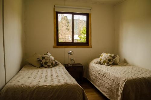 a bedroom with two beds and a window at Refugio Simple Sur Casa 6 personas in Malalcahuello