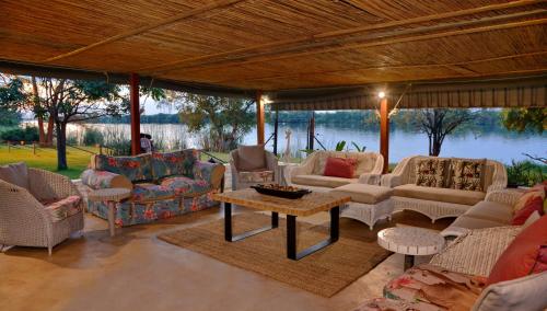 a living room with couches and a table with a view at River View Lodge in Kasane