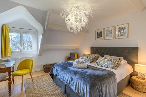 a bedroom with a bed and a chandelier at Ty-Voli - Magnifique Longère rénovée in Plougoumelen