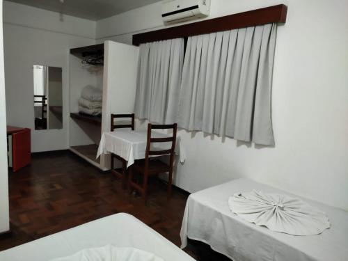 a room with two beds and a table and a window at Hotel Firenze in Londrina