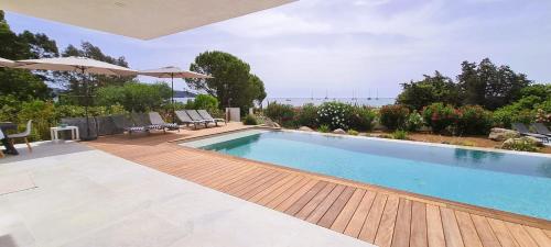 een groot zwembad met een houten terras en een overloop bij Villa Acqua 12 pers piscine chauffée accès direct plage in Lecci
