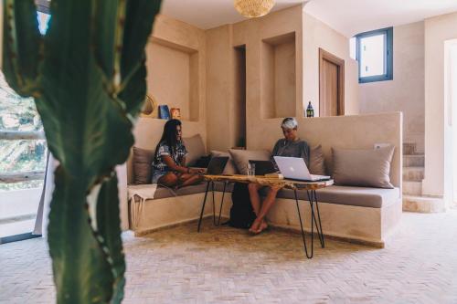 zwei Leute sitzen auf einer Couch mit ihren Laptops in der Unterkunft Surf&Sound Hotel in Imsouane