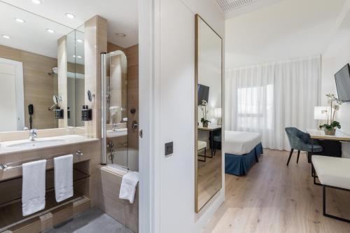 a bathroom with a sink and a shower and a desk at Eurostars Gran Madrid in Alcobendas