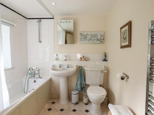 a bathroom with a sink and a toilet and a bath tub at The Hay Loft in Colyton