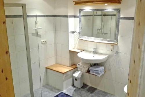 La salle de bains blanche est pourvue d'un lavabo et d'une douche. dans l'établissement Bergbauernhof Simmerl, à Sachrang