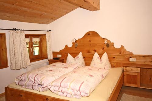 a bedroom with a large bed with a wooden headboard at Bergbauernhof Simmerl in Sachrang