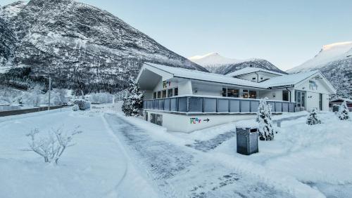 a house covered in snow with mountains in the background at Loen Apartments in Loen