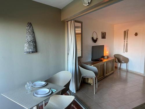 Una sala de estar con una mesa y sillas y un televisor. en - Les pieds dans l'eau à 50m de la plage, côté mer caraïbe - Domaine de l'Anse CARITAN - Sainte-Anne -, en Sainte-Anne