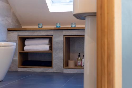 a bathroom with a shelf with towels and a toilet at Stunning rural stay with idyllic views & great location in Talacre