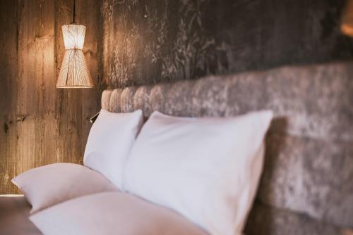 a bed with two white pillows and a lamp at Margarethenstein Boutique Hotel in Kaprun