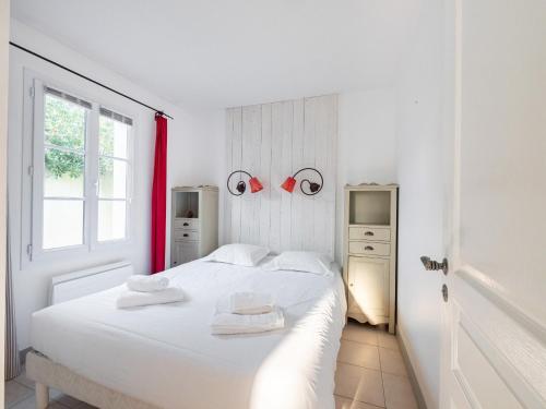 a white bedroom with a white bed and a window at Charmante maison avec piscine partagee in Le Bois-Plage-en-Ré