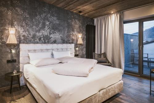 a bedroom with a large white bed and a balcony at Margarethenstein Boutique Hotel in Kaprun