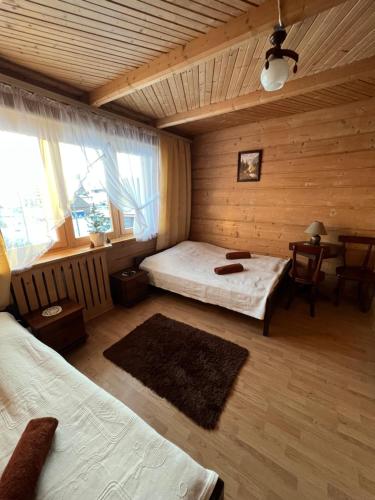 ein Schlafzimmer mit 2 Betten und einem Tisch in einem Zimmer in der Unterkunft Dom Wypoczynkowy Anetka in Białka Tatrzańska