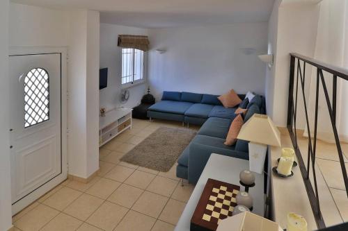 ein Wohnzimmer mit einem blauen Sofa in einem Zimmer in der Unterkunft Casa Vale do Lobo 32 - Charming Townhouse AC 2 minutes walk from Beach Praca in Vale do Lobo