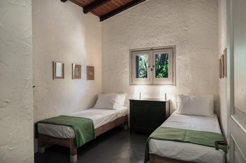 two twin beds in a room with a window at Dimoulitsa Villas Complex in Doukádes