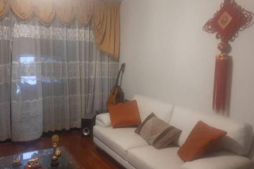 sala de estar con sofá blanco y guitarra en Amplio Departamento Residencial en La Molina, en Lima