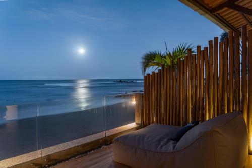 a couch on a balcony with a view of the ocean at Pousada Dona Moça in Morro de São Paulo