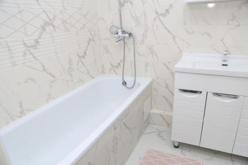a white bathroom with a tub and a sink at Апартаменты в центре Бишкека in Bishkek