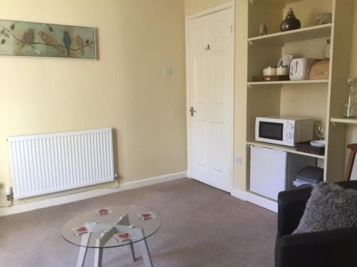 a living room with a coffee table and a microwave at Bens Hollow with hot tub in Bredon