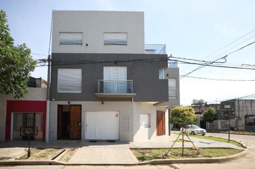 una gran casa blanca con un coche aparcado delante de ella en Departamento de un dormitorio - SAN LORENZO en Santa Fe