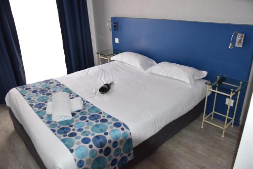a bedroom with a large bed with a blue headboard at Hôtel Bel Azur in Six-Fours-les-Plages