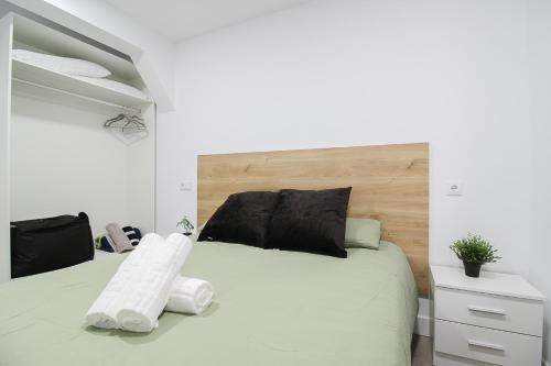 a bedroom with a white bed with a wooden headboard at La Maruca Beach Santander in Santander